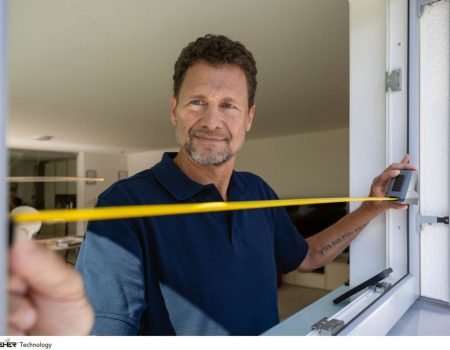 Insektenschutz. Ein Mann nimmt Aufmaß am Fenster.