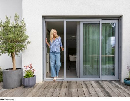 Insektenschutz. Eine Frau steht an einer Terassentür.